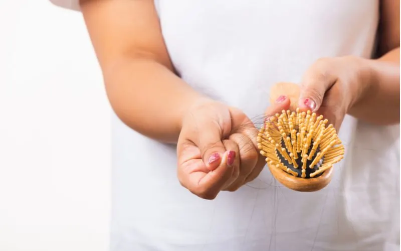 For a piece on how to clean a hair brush, a woman pulling hair from the teeth of her wooden bristled brush