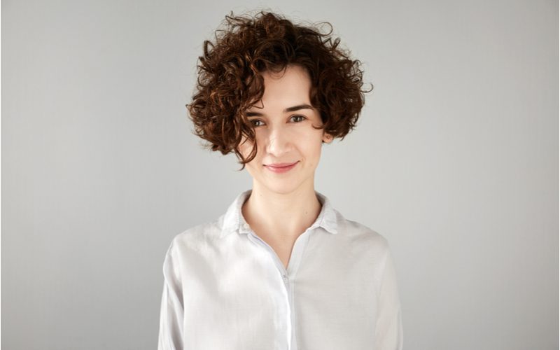 Portrait of a young hipster woman in a white shirt with short curly hair