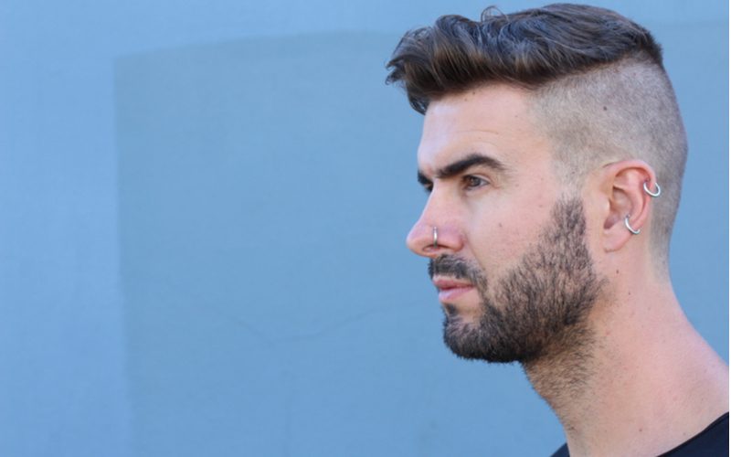 Guy with an undercut fade with beard stand in a blue room