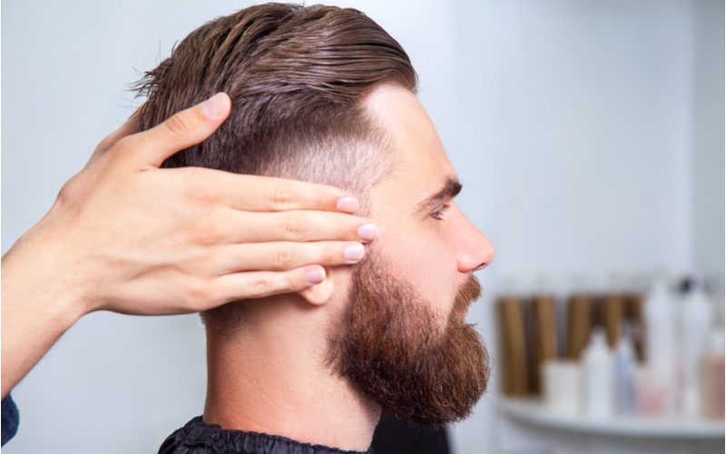 Man with an undercut fade and thick beard gets shampooed by a hairstylist