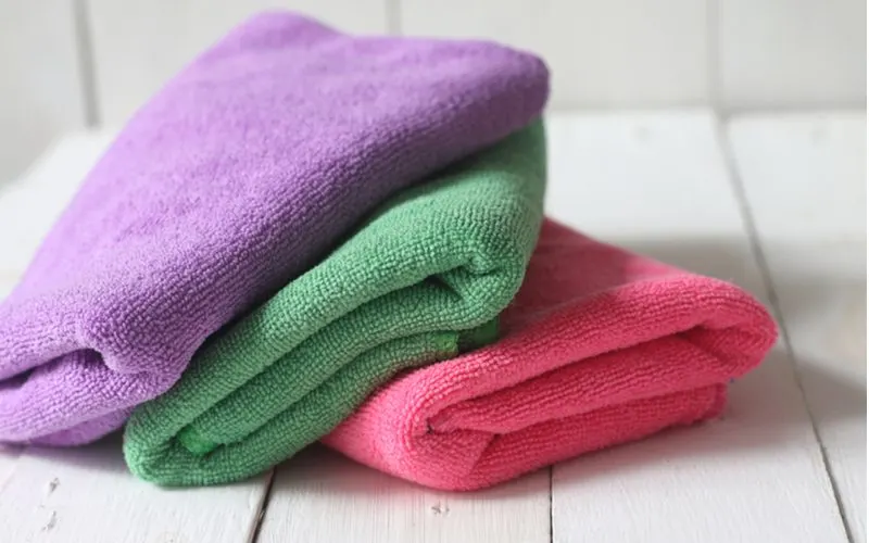 As an image for the step on getting rid of frizzy hair, a few colorful microfiber towels sit on a white wooden table