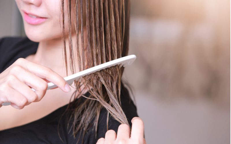 Người phụ nữ chải tóc cho một bước trong quy trình làm thế nào để loại bỏ kẹo cao su ra khỏi tóc