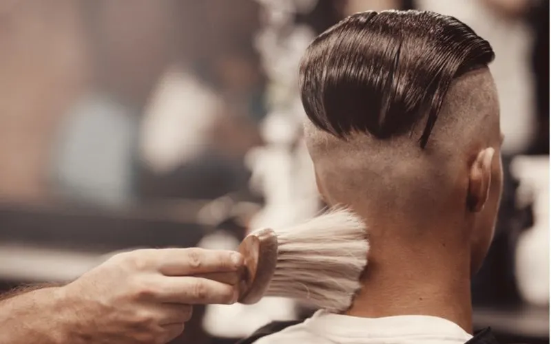 Man in a barber's chair rocking a slicked-back undercut fade haircut
