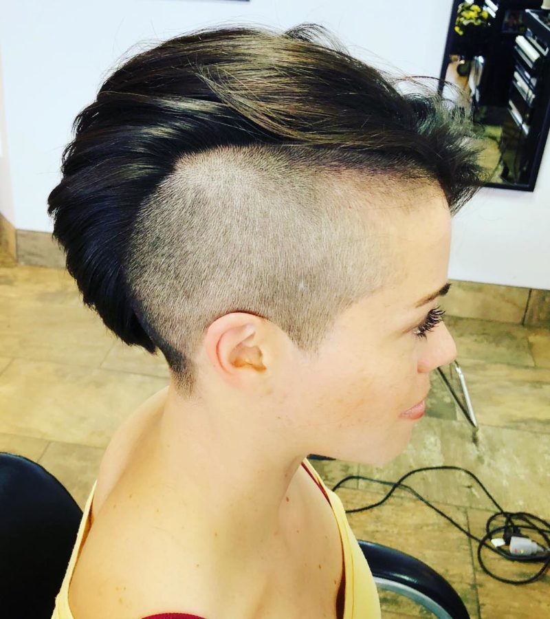 Female mohawk on a woman with a shaved head with pretty long eyelashes in a yellow shirt