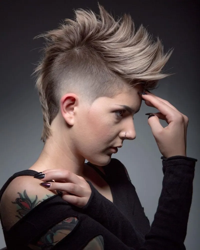 Woman with a female mohawk that's spiked up holding her forehead