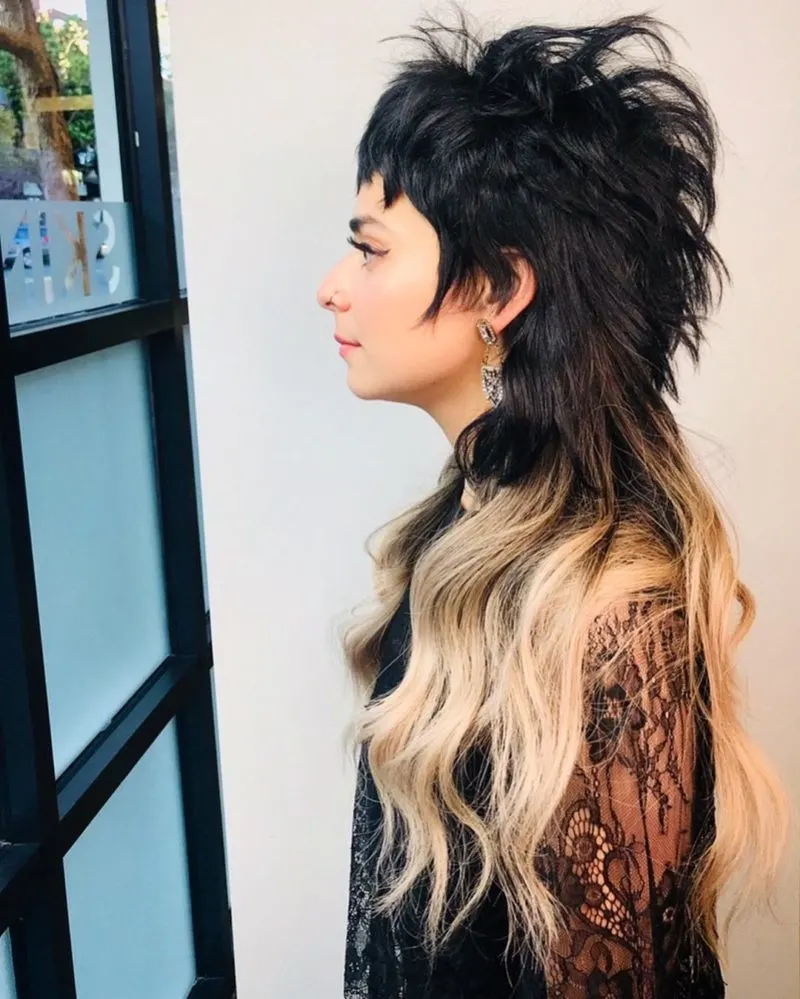 Female mohawk mullet on a girl in a lace sleeved shirt and dyed tips looking out a window