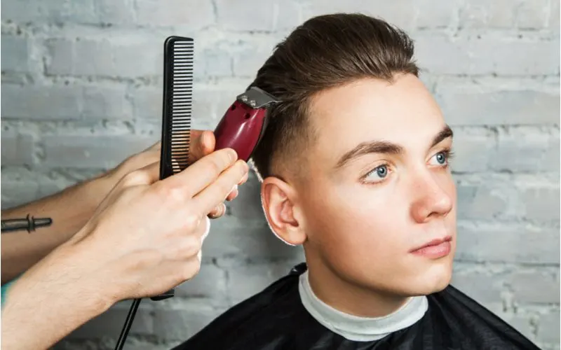Guy With Slicked-Back Hair With Undercut Getting shaved from a set of red electric clippers