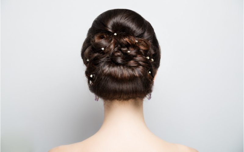 Woman with a mother of the groom hairstyle, a pinned updo, shows the photographer the back of her head in a close-up image