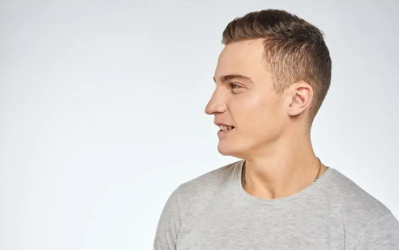 Guy with a pompadour hairstyle in a grey shirt looking to his right