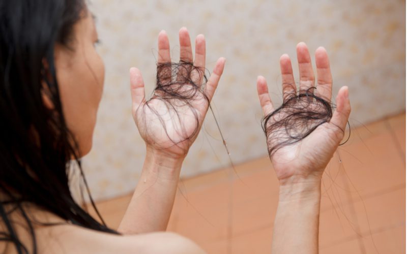 Woman holding her hands because her hair is shedding as the result of COVID-19 hair loss