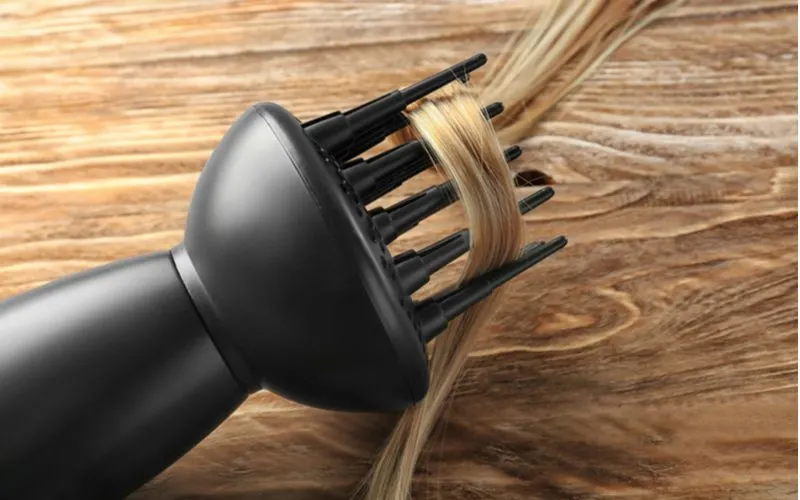To symbolize what a hair diffuser does, a strand of blonde hair wrapped around its teeth