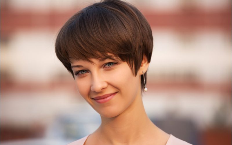 Woman with a pixie bob haircut standing outside with earrings
