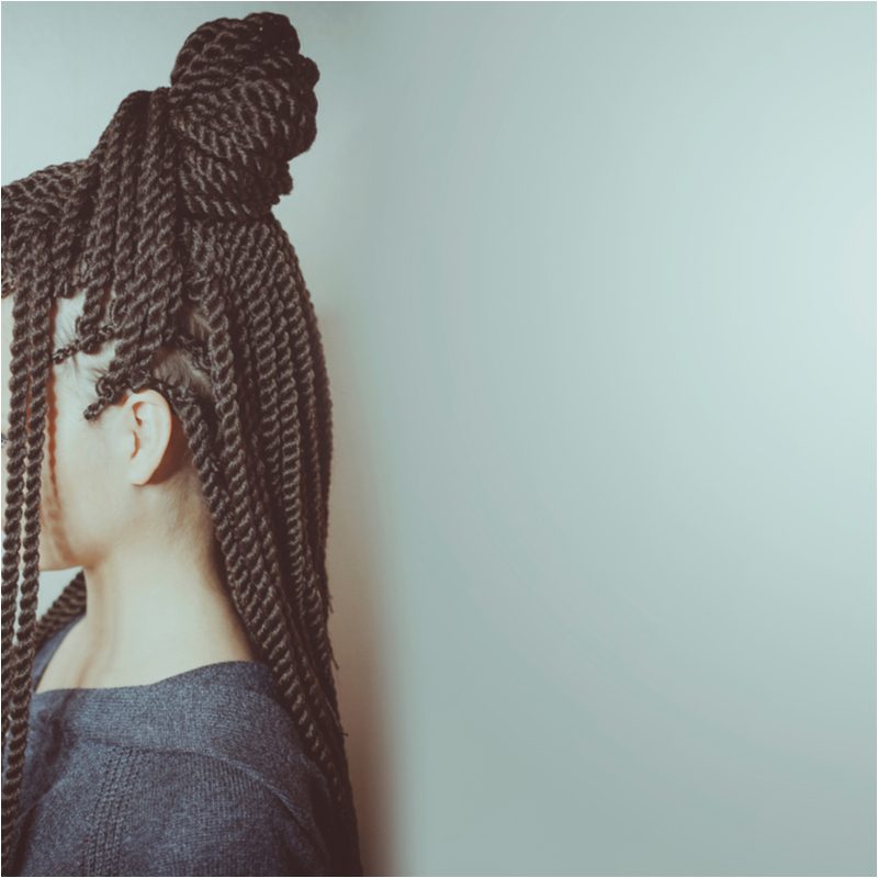 Woman with half-up hanging twists looks to the side of the camera
