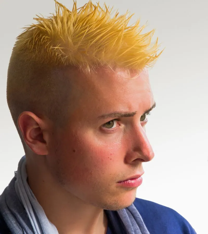 Bleach-Blonde Faux Hawk on a guy with orange hair wearing a blue shirt with a scarf and looking to the right of the reader