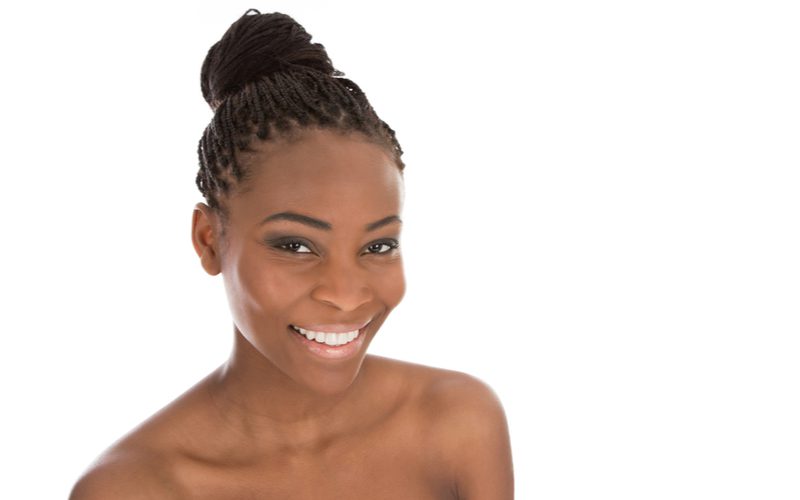 One of our favorite black hairstyles for woman, faux locks with a bun, on a topless woman in a white studio