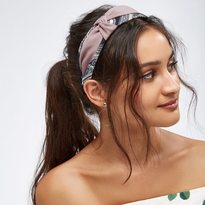 Woman with a headband looks to her left after showing us how to cut curtain bangs