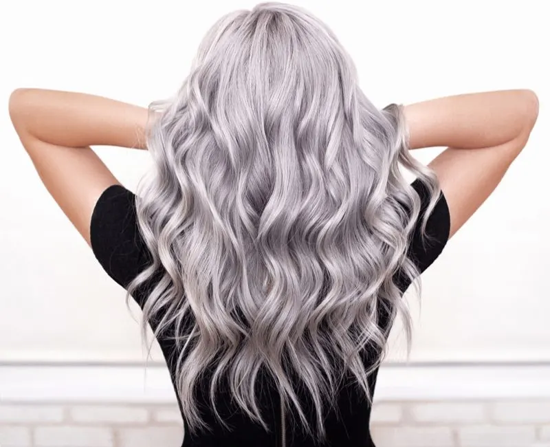 Beautiful girl showing us how to get silver hair while holding her arms up below her hair while wearing a black shirt