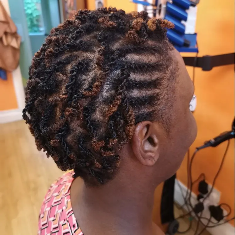Black woman with micro kinky twists sits in a braiding salon smiling