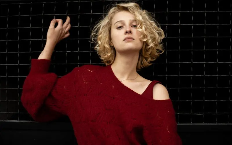 Woman with an over-the-shoulder red sweater wearing a curly bob