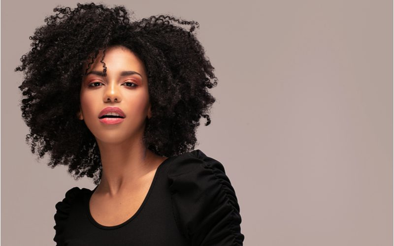 Side-Swept Layered Coils black hairstyle for women on a pretty gal in a ruffled sleeve black shirt