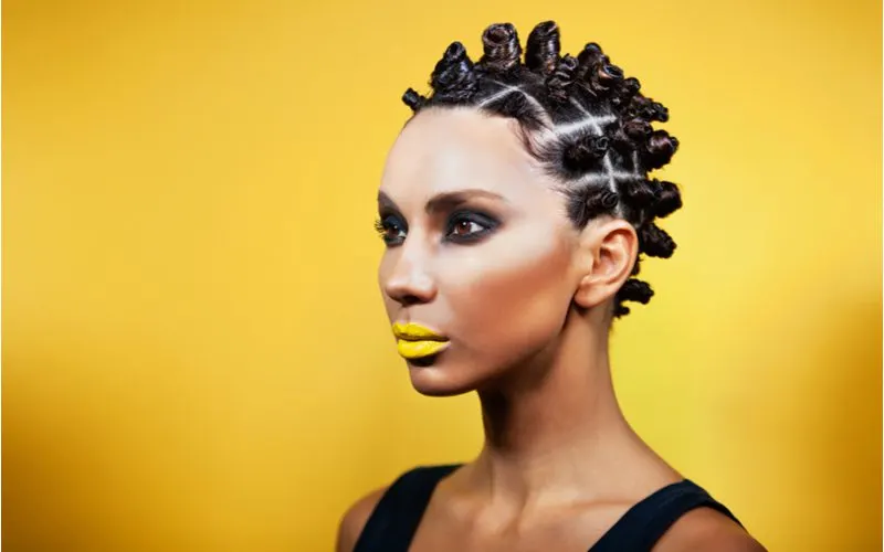Zulu knots on a woman with spikey hair standing in a yellow room