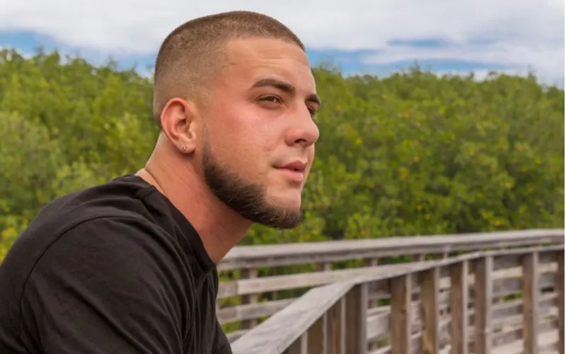 Buzzcut With Chinstrap Beard hairstyle on a guy on a wooden walkway