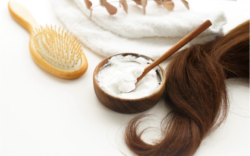 For a piece on how to lighten hair without bleach, a number of hair products sit on a counter next to a long strand of brown hair