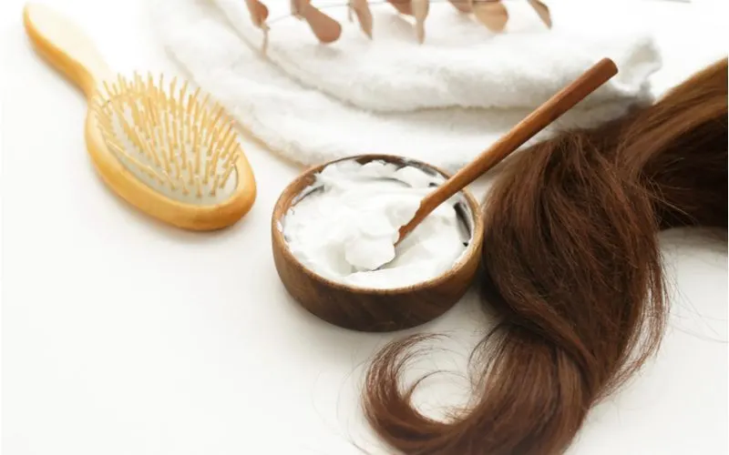 For a piece on how to lighten hair without bleach, a number of hair products sit on a counter next to a long strand of brown hair