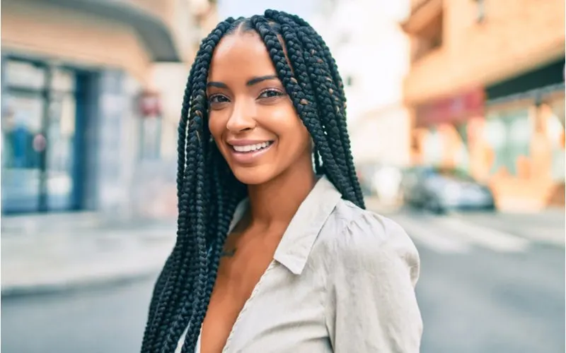 Woman with box braids in business casual attire standing by a street crosswalk