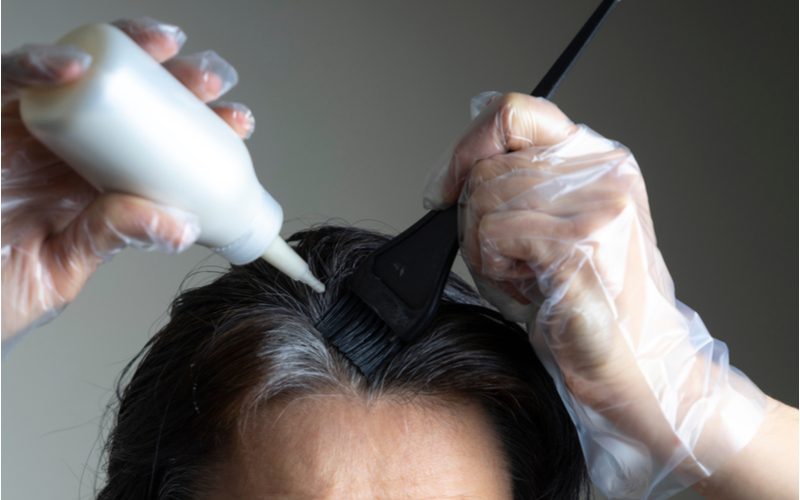 Để biết về thời gian nhuộm tóc tại nhà mất bao lâu, một phụ nữ đổ bộ dụng cụ nhuộm tóc DIY lên lược chải tóc
