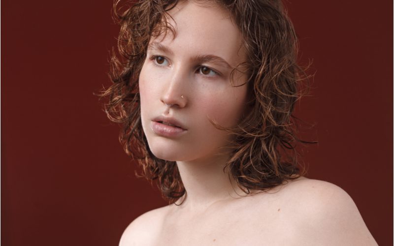 Wet-Cut Curly Lob on a woman in a burgundy room