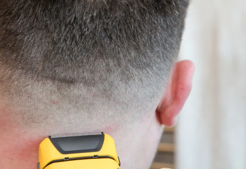 Close up of a guy getting a faded buzzcut from a yellow set of clippers