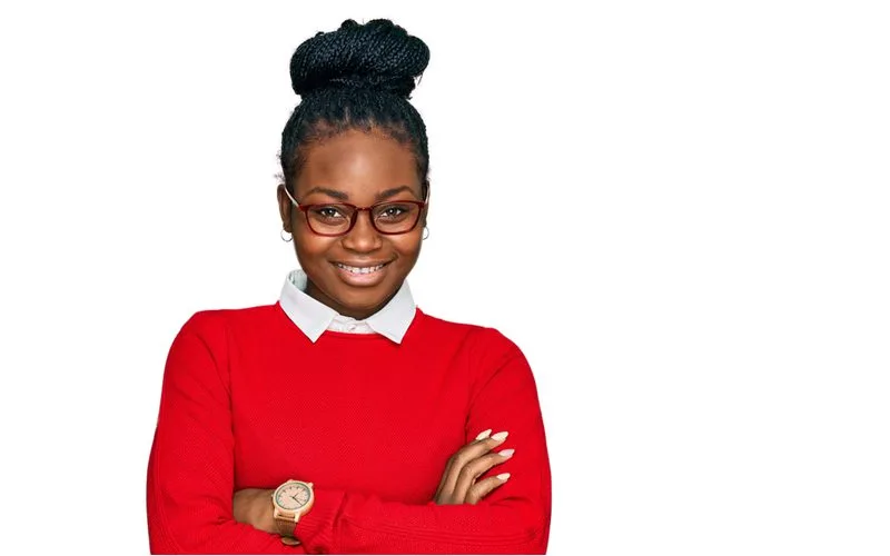 Sleek Braided Bun with box braids on a woman crossing her arms wearing a red sweater