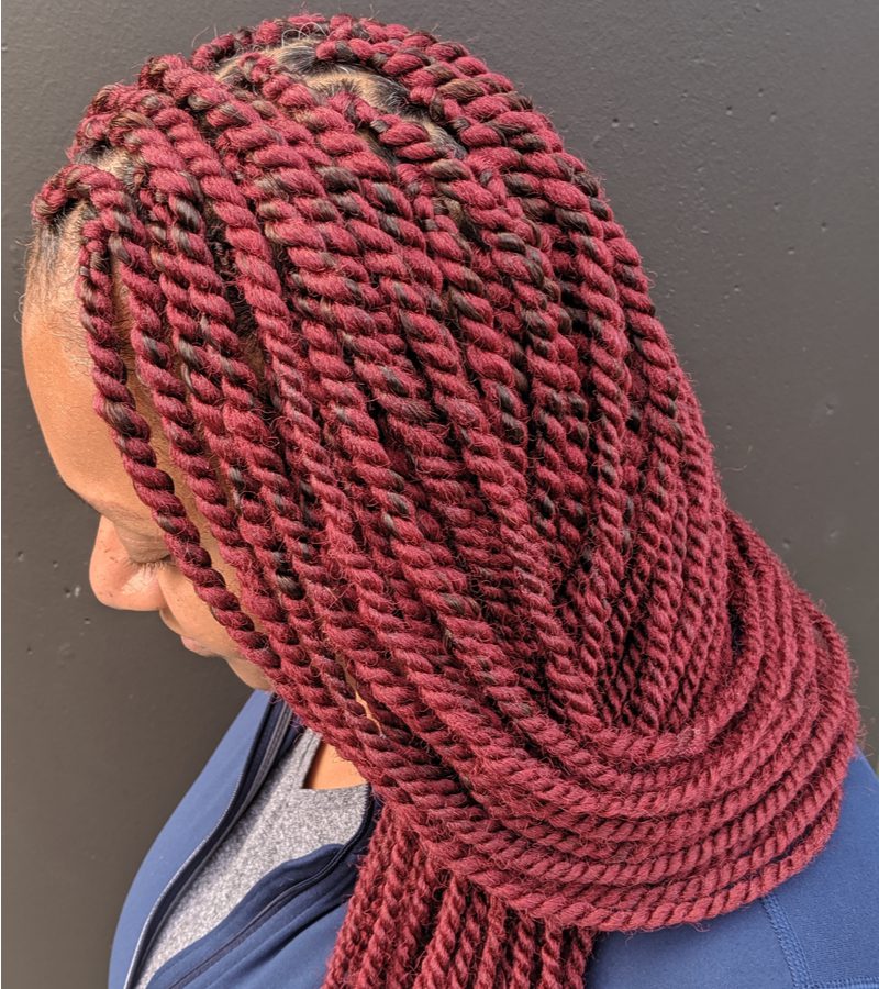 Young African American woman with kinky twists and red braided hair sits in business professional dress