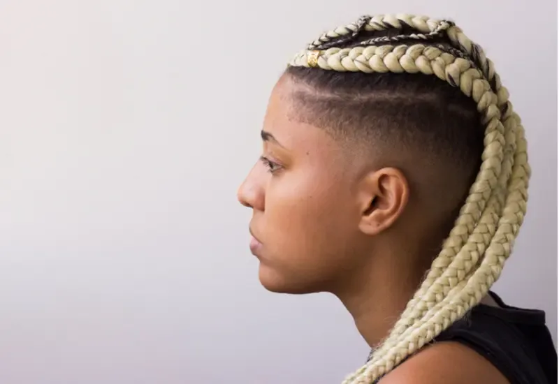 For a piece on tribal braids, a woman with dutch braids that are dyed blonde and pulled back with a shaved side