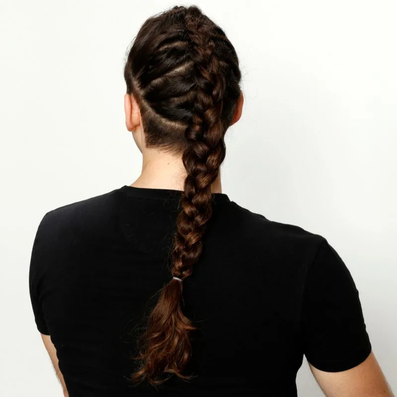 Guy in a black crew neck tshirt wearing a French to Four-Strand braid for men and standing in a studio