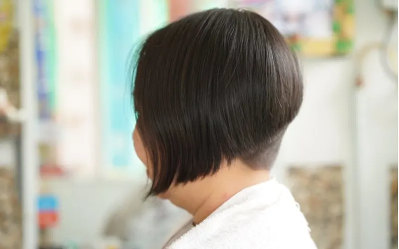 Spiral undercut asymmetrical bob haircut on a woman looking ahead in a classroom as a side profile