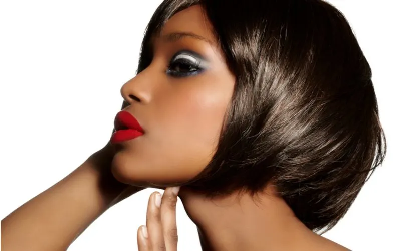 Relaxed and layered bob haircut on a black woman with red lips standing in a white room