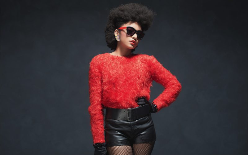 Black woman wearing a picked-out afro in a red shirt and black leather pants