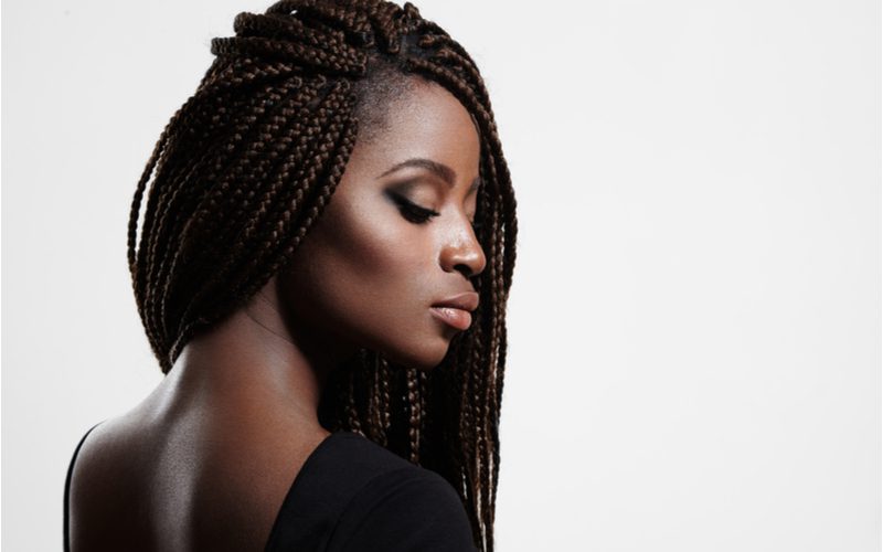 Woman with flowing long box braids looks over her right shoulder