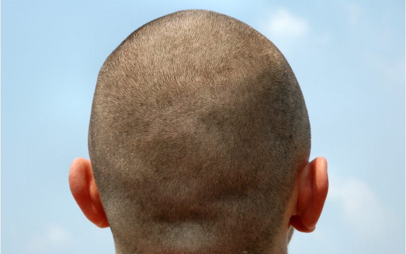 Guy with a buzz cut looks away from the camera into the blue sky