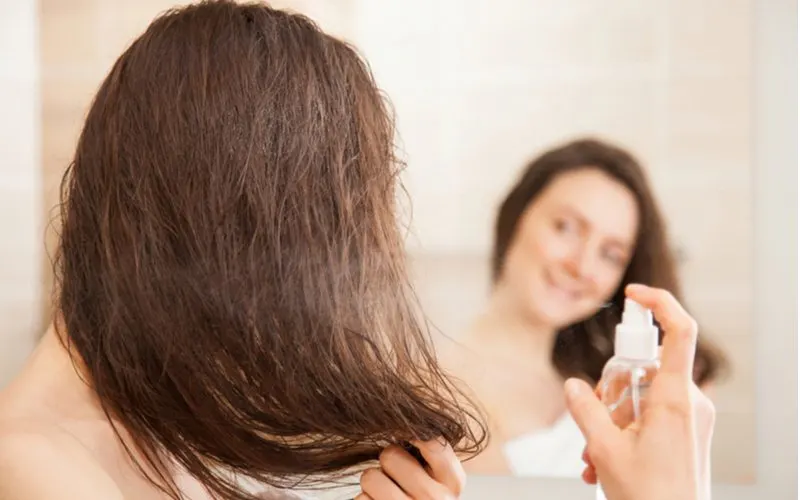 Smiling woman applying pre-treatment spray to her hair before diffusing