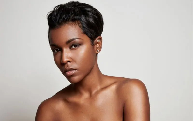 Relaxed pixie bob haircut on a black woman who's not wearing a shirt