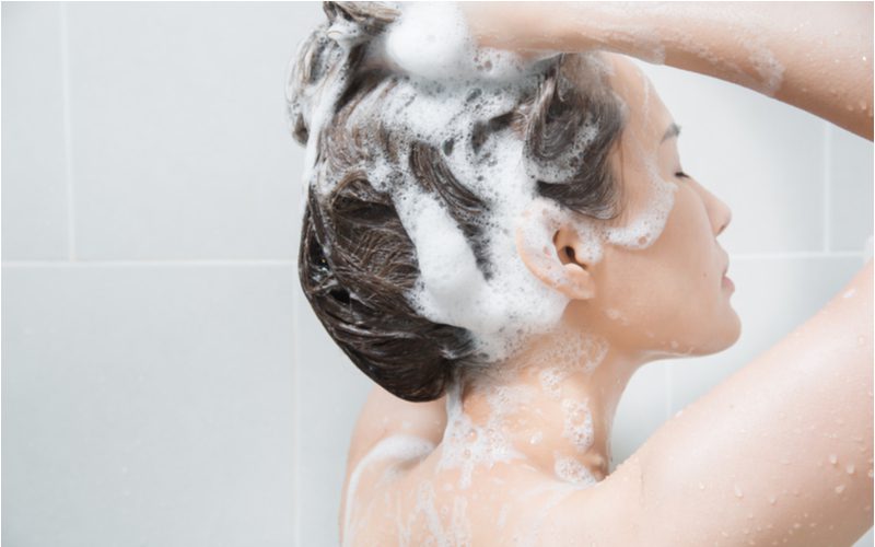 Asian woman shampooing her hair in preparation for teasing it once its dry and clean