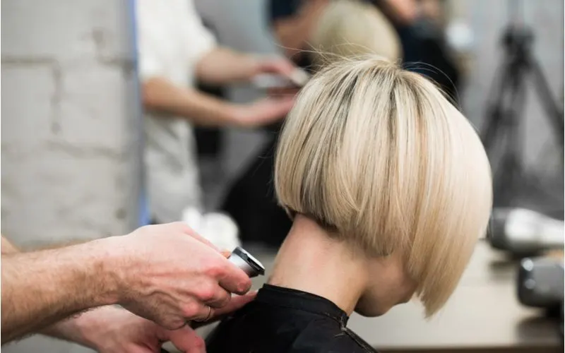 Inverted Blonde Bob on a woman in a salon chair getting her neckline shaved