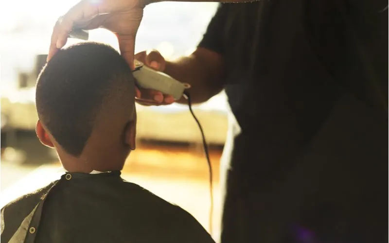 Black kid in a barber chair getting a Buzzcut With Angled Back