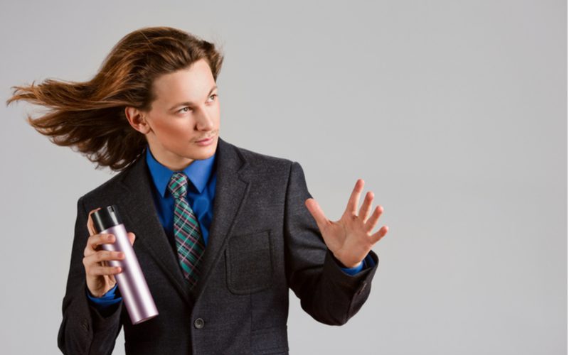 Feathered hair on a man in a suit holding a can of hair spray