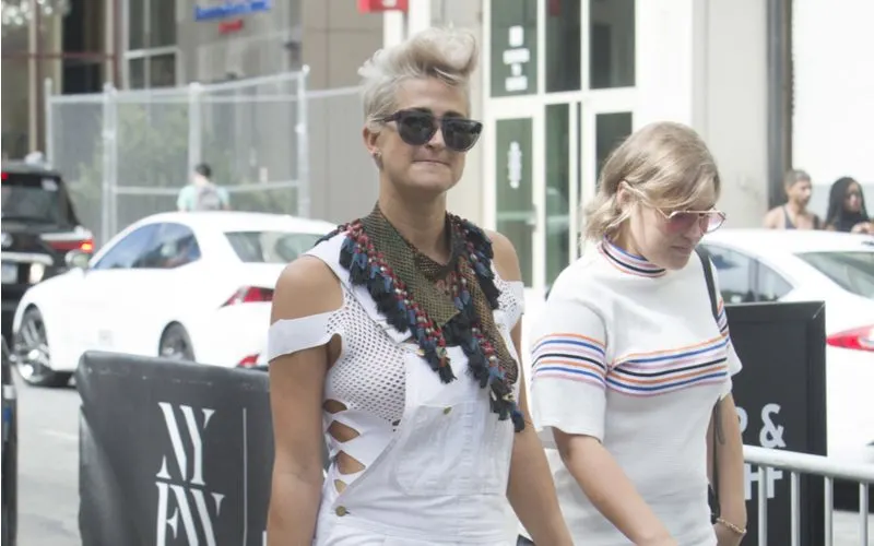 Woman with a punk rock faux hawk haircut in white overalls and a white bra walking on the street in NYC