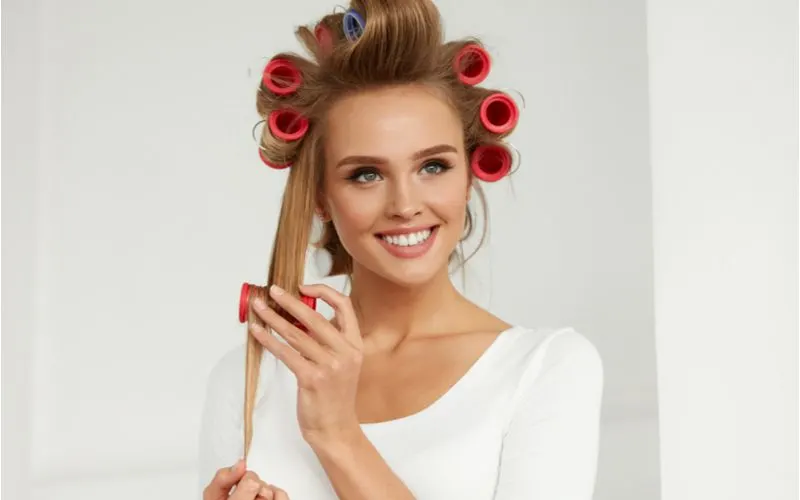 Image of a woman learning how to use hair rollers while pulling a strand of hair down to put into a roller