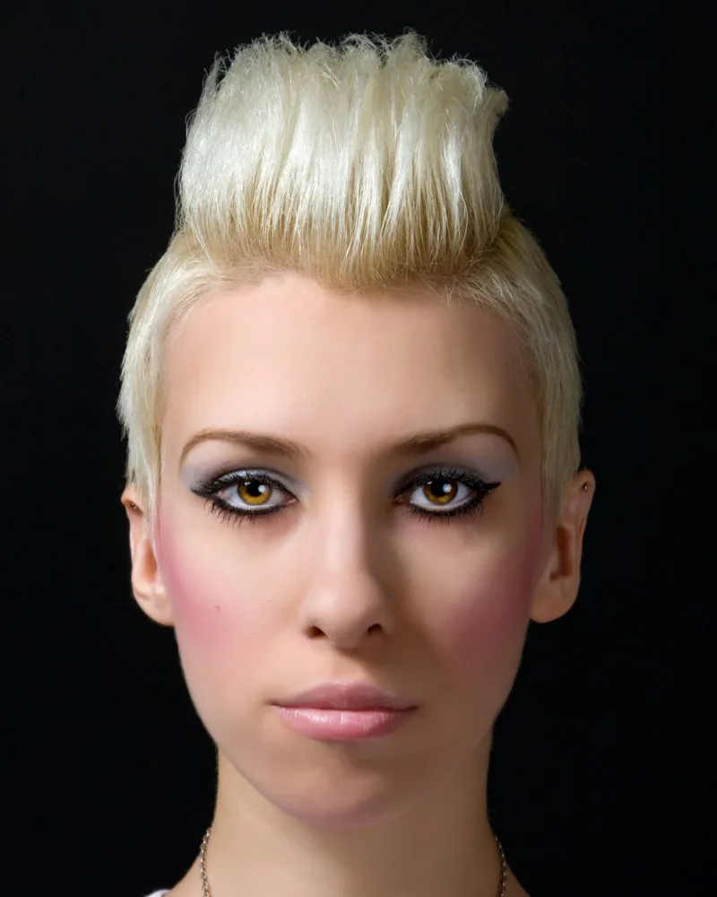 Platinum Psychobilly Wedge punk hairstyle on a woman in a black room with platinum blonde hair